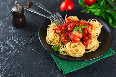 Spagetti makarna köfte, domates sosu ve fesleğen koyu arka plan üzerinde.