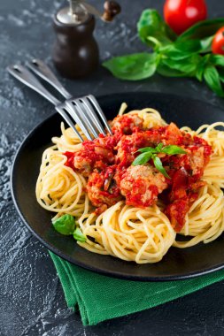 Spagetti makarna köfte, domates sosu ve fesleğen koyu arka plan üzerinde.