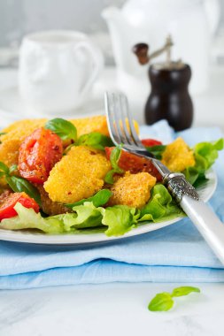 Kızarmış peynir domates ve marul hafif bir arka plan üzerine pişmiş mısır ezmesi, dilim. Kahvaltı konsepti.