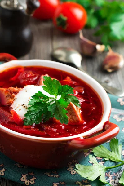 Rote-Bete-Suppe mit Fleisch, saurer Sahne und Petersilie in einer braunen Keramikschüssel auf altem Holzgrund. Borschtsch - traditionelles Gericht der ukrainischen Küche. — Stockfoto