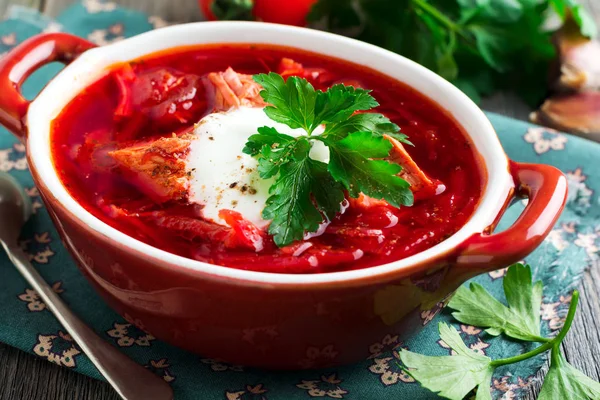 Rote-Bete-Suppe mit Fleisch, saurer Sahne und Petersilie in einer braunen Keramikschüssel auf altem Holzgrund. Borschtsch - traditionelles Gericht der ukrainischen Küche. — Stockfoto