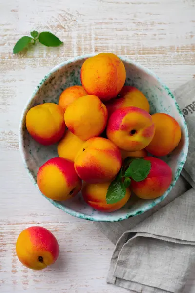 Fresh juicy fruit nectarines in metal grid on  white wooden background. — Stock Photo, Image