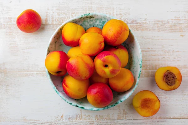 Nectarinas de frutas jugosas frescas en rejilla metálica sobre fondo de madera blanca . — Foto de Stock