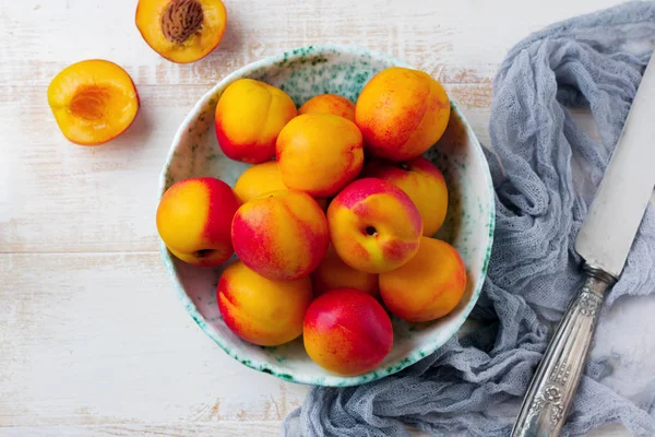 Vers, sappig fruit nectarines in metalen raster op witte houten achtergrond. — Stockfoto