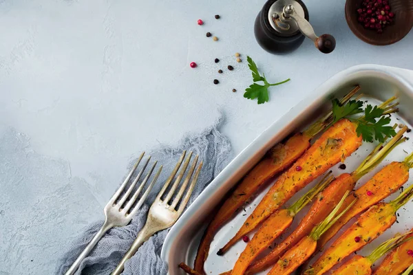 Запеченные морковь со специями, чеснок и оливковое масло в простой алюминиевой форме на сером бетонном фоне . — стоковое фото
