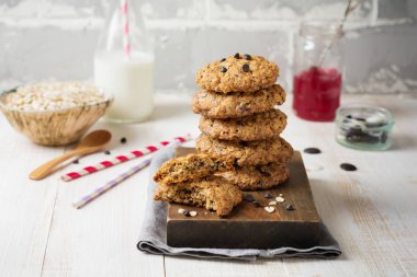 Yulaf ezmeli kurabiye çikolata üzerinde pul ve bir şişe süt hafif bir arka plan ile yığını. 