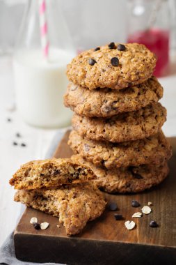 Yulaf ezmeli kurabiye çikolata üzerinde pul ve bir şişe süt hafif bir arka plan ile yığını. 