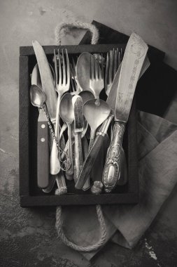 Vintage çatal, kaşık ve bıçak bir gri beton veya taş arka plan üzerinde koyu eski ahşap kutu içinde. 