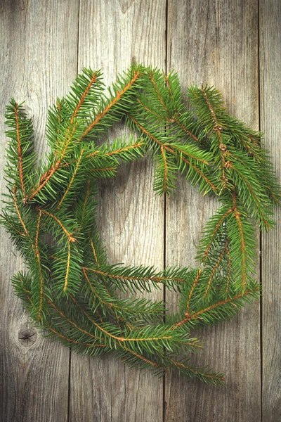 Corona de Navidad simple hecha de ramas de abeto sobre un viejo fondo de madera vintage . — Foto de Stock