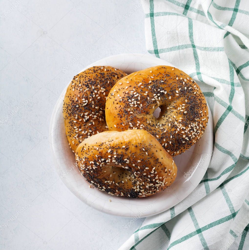 Bagels in a ceramic old bowl with a textile napkin on a light stone or concrete background. 