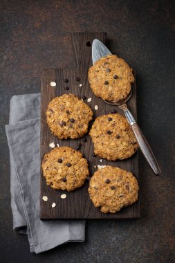 Yulaf ezmeli kurabiye çikolata ve karanlık paslı beton veya taş arka plan üzerinde pul ile yığını.