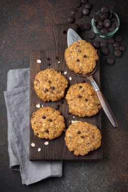 Yulaf ezmeli kurabiye çikolata ve karanlık paslı beton veya taş arka plan üzerinde pul ile yığını.