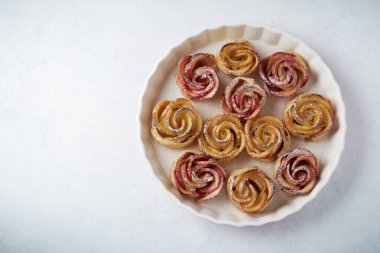 Bir elma ile lezzetli börek seramik formunda hafif bir beton veya taş arka plan üzerinde yükseldi.. 