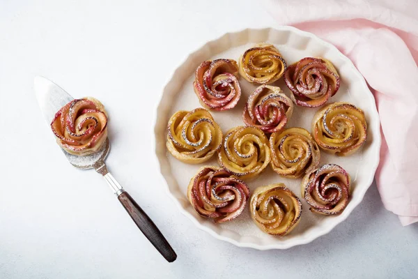 Delicious pies with an apple rose in ceramic form on a light concrete or stone background. — Stock Photo, Image