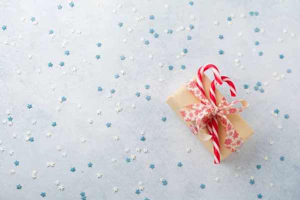 Christmas candy, gift box and confectioner\'s multicolored powder on light stone or concrete background.