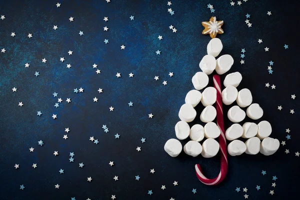 Kerstboom snoep, ontbijtkoek, marshmallows en suikerbakkerij veelkleurige poeder op donker blauwe steen of beton achtergrond — Stockfoto