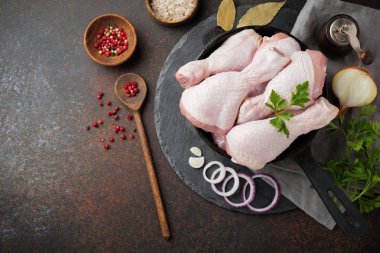 Baharatlar ve otlar pişirme için hazırlanan eski ahşap arka plan üzerinde bir dökme demir tencere üzerinde çiğ tavuk budu. Seçici odak.