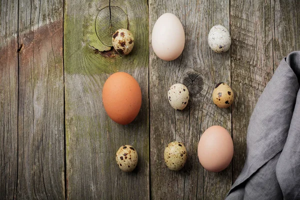 全体のウズラし、鶏の古い木製テクスチャの背景に小さな鋳鉄製のフライパンで卵. — ストック写真
