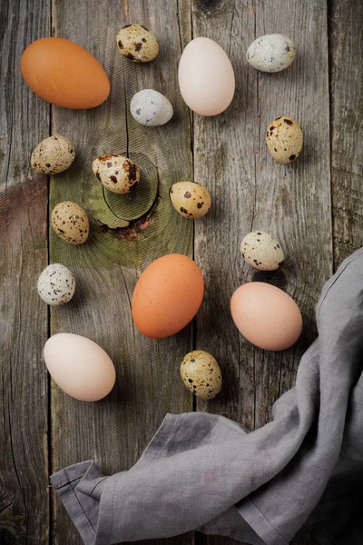 Burung puyuh dan telur ayam dalam wajan besi cor kecil di latar belakang tekstur kayu tua . — Stok Foto