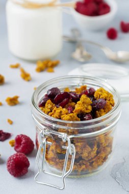 Granola kabak ve kurutulmuş meyve sağlıklı bir kahvaltı için bir ışık taş veya beton arka plan cam kavanozda.