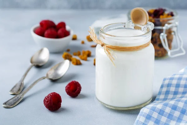 Świeży jogurt naturalny w szklanym słoju na jasnym tle drewnianych. — Zdjęcie stockowe