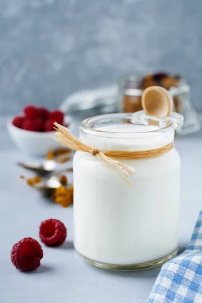 Fresh natural yogurt in a glass jar on  light wooden background. — Stock Photo, Image