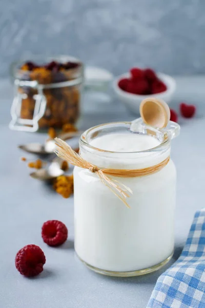 Fresh natural yogurt in a glass jar on  light wooden background. — Stock Photo, Image