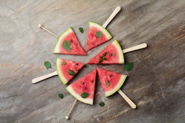 Taze çiğ karpuz parçalar halinde gri taş zemin üzerine kesilmiş..