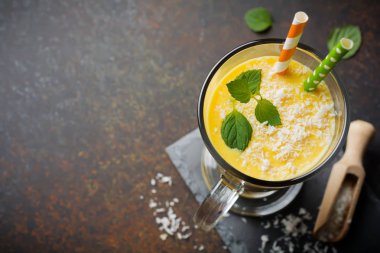 Kabak smoothies zencefil ve hindistancevizi talaşı ve nane bir cam bir karanlık taş veya beton arka plan ile. Sağlıklı ve lezzetli kahvaltı içmeye. Seçici odak. Üstten Görünüm. Kopya alanı.