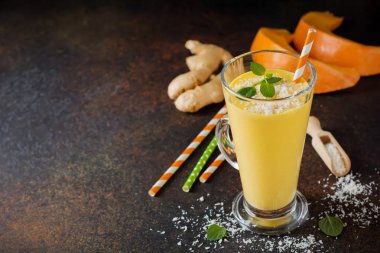 Kabak smoothies zencefil ve hindistancevizi talaşı ve nane bir cam bir karanlık taş veya beton arka plan ile. Sağlıklı ve lezzetli kahvaltı içmeye. Seçici odak. Üstten Görünüm. Kopya alanı.