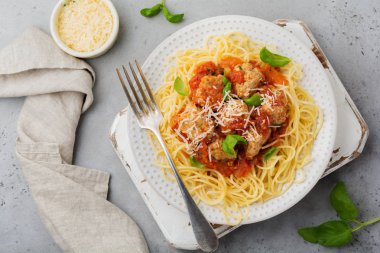 Domates Sos, parmesan peyniri, fesleğen ve gri beton veya taş zemin üzerine beyaz seramik plaka üzerinde köfte makarna spagetti. Seçici odak. Üstten Görünüm.