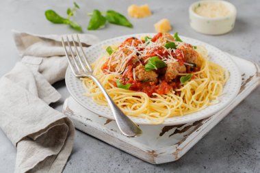 Domates Sos, parmesan peyniri, fesleğen ve gri beton veya taş zemin üzerine beyaz seramik plaka üzerinde köfte makarna spagetti. Seçici odak. Üstten Görünüm.
