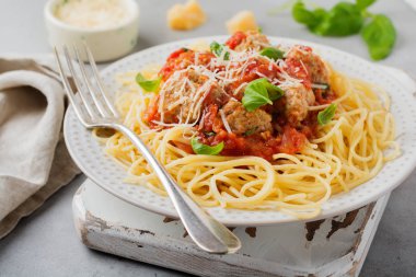 Domates Sos, parmesan peyniri, fesleğen ve gri beton veya taş zemin üzerine beyaz seramik plaka üzerinde köfte makarna spagetti. Seçici odak. Üstten Görünüm.