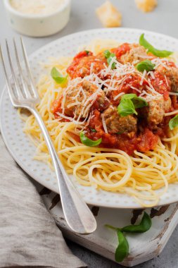 Domates Sos, parmesan peyniri, fesleğen ve gri beton veya taş zemin üzerine beyaz seramik plaka üzerinde köfte makarna spagetti. Seçici odak. Üstten Görünüm.