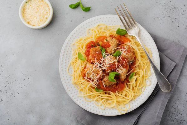 Domates Sos, parmesan peyniri, fesleğen ve gri beton veya taş zemin üzerine beyaz seramik plaka üzerinde köfte makarna spagetti. Seçici odak. Üstten Görünüm.