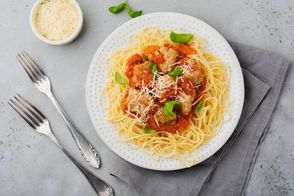 Domates Sos, parmesan peyniri, fesleğen ve gri beton veya taş zemin üzerine beyaz seramik plaka üzerinde köfte makarna spagetti. Seçici odak. Üstten Görünüm.