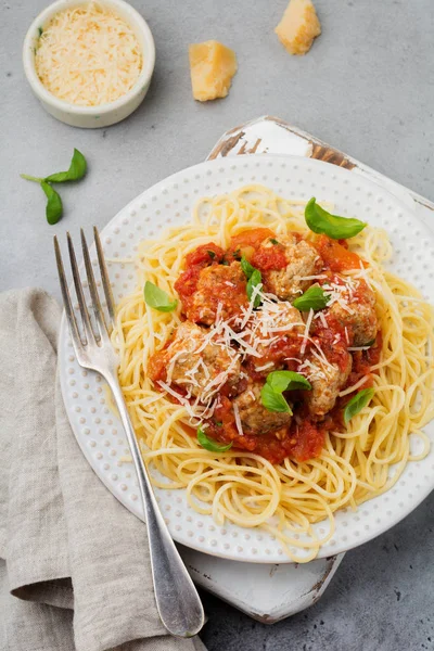 Domates Sos, parmesan peyniri, fesleğen ve gri beton veya taş zemin üzerine beyaz seramik plaka üzerinde köfte makarna spagetti. Seçici odak. Üstten Görünüm.