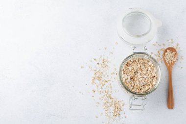 Hafif bir arka plan üzerinde bir cam kavanoza çiğ yulaf gevreği. Yulaf ezmesi. Seçici odak. Üstten Görünüm. Kopya alanı.