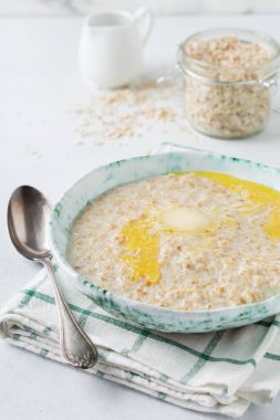 Tereyağı bir ışık taş veya beton arka plan bir seramik tabak yulaf ezmesi. Seçici odak.