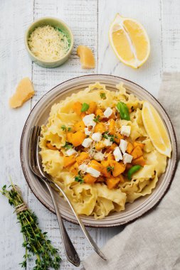 Fırında kabak, beyaz peynir ve baharat otlar Beyaz ahşap zemin üzerinde seramik plaka ile makarna Mafaldine Napoletane. Seçici odak. Rustik tarzı. Üstten Görünüm.