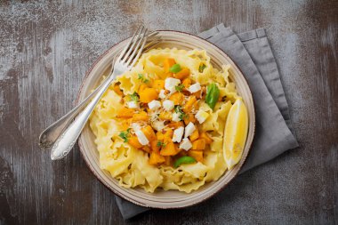 Fırında kabak, beyaz peynir ve baharat otlar gri beton eski arka plan üzerinde seramik plaka ile makarna Mafaldine Napoletane. Seçici odak. Rustik tarzı. Üstten Görünüm.