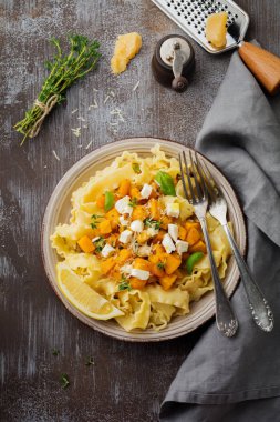 Fırında kabak, beyaz peynir ve baharat otlar gri beton eski arka plan üzerinde seramik plaka ile makarna Mafaldine Napoletane. Seçici odak. Rustik tarzı. Üstten Görünüm.