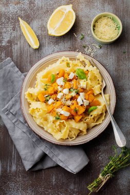 Fırında kabak, beyaz peynir ve baharat otlar gri beton eski arka plan üzerinde seramik plaka ile makarna Mafaldine Napoletane. Seçici odak. Rustik tarzı. Üstten Görünüm.