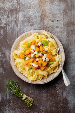 Fırında kabak, beyaz peynir ve baharat otlar gri beton eski arka plan üzerinde seramik plaka ile makarna Mafaldine Napoletane. Seçici odak. Rustik tarzı. Üstten Görünüm.