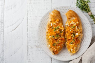 Bruschetta pişmiş kabak, beyaz peynir ile ışık ahşap zemin üzerine kekik. Baharatlı balkabağı sandviç. Seçici odak. Üstten Görünüm.