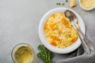 Kekikli balkabaklı risotto, sarımsak, parmesan peyniri ve gri beton ya da taş zemin üzerinde beyaz şarap. Seçici odaklanma. Kırsal tarzda. Üst görünüm.