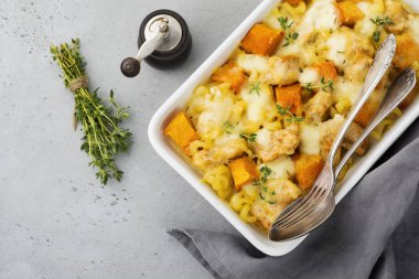 Tavuk eti, kabak, makarna, kekik, peynir ve hafif beton veya taş zemin üzerine seramik formundaki Beşamel sos güveç. Seçici odak. Üstten Görünüm. Kopya alanı.