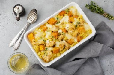 Tavuk eti, kabak, makarna, kekik, peynir ve hafif beton veya taş zemin üzerine seramik formundaki Beşamel sos güveç. Seçici odak. Üstten Görünüm. Kopya alanı.