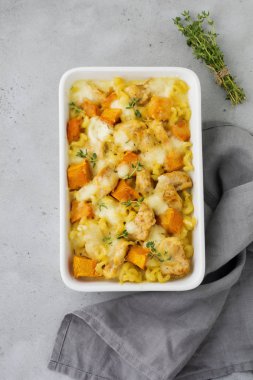 Tavuk eti, kabak, makarna, kekik, peynir ve hafif beton veya taş zemin üzerine seramik formundaki Beşamel sos güveç. Seçici odak. Üstten Görünüm. Kopya alanı.