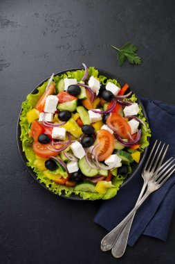 Yunan salatası siyah beton zemin üzerine seramik plaka. Geleneksel Yunan yemeği. Seçici odak. Üstten Görünüm.